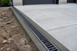 Caniveau d'évacuation d'eau pluviale installé le long d'une allée en béton